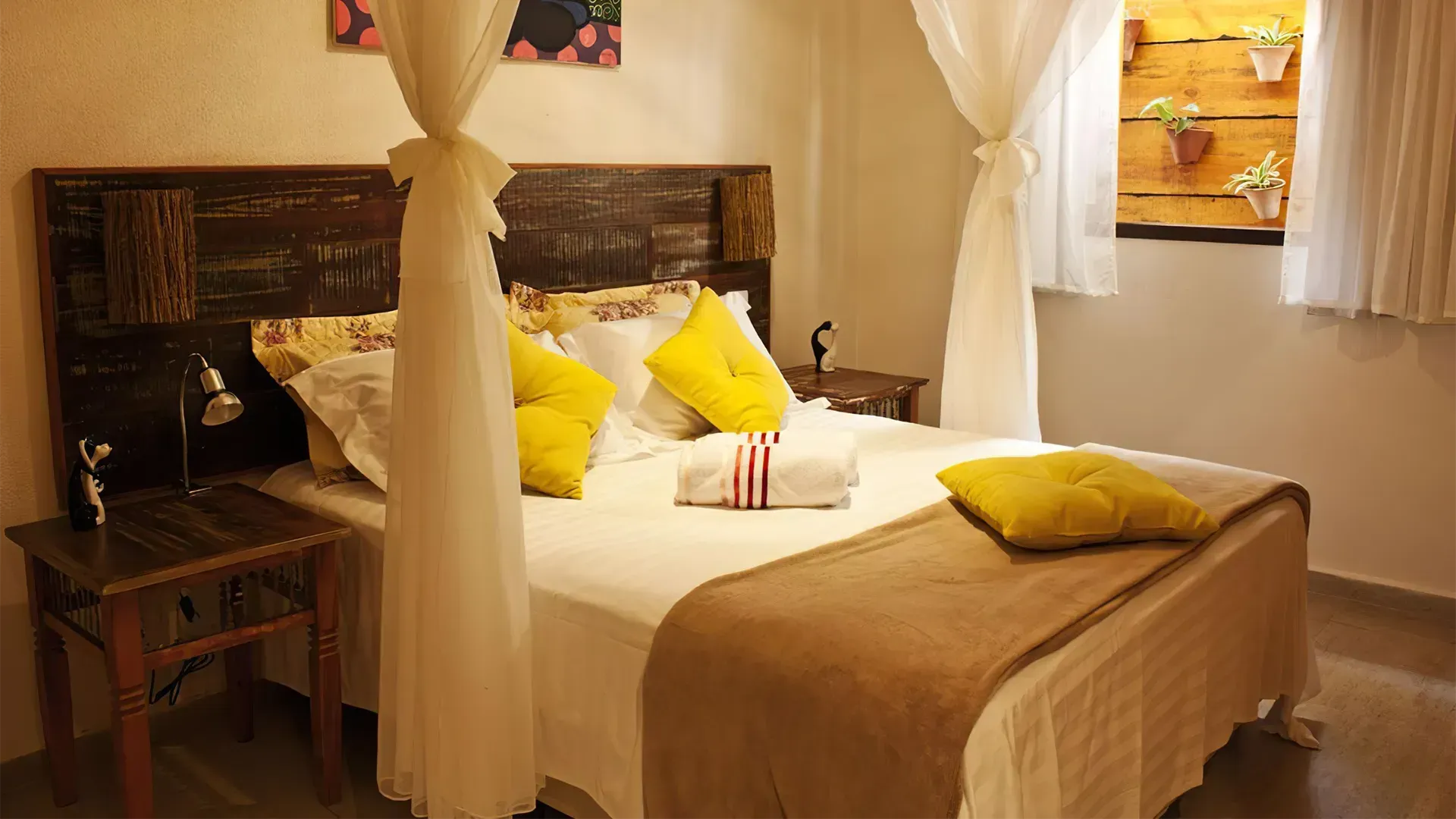 Um quarto com cama de dossel e travesseiros amarelos.