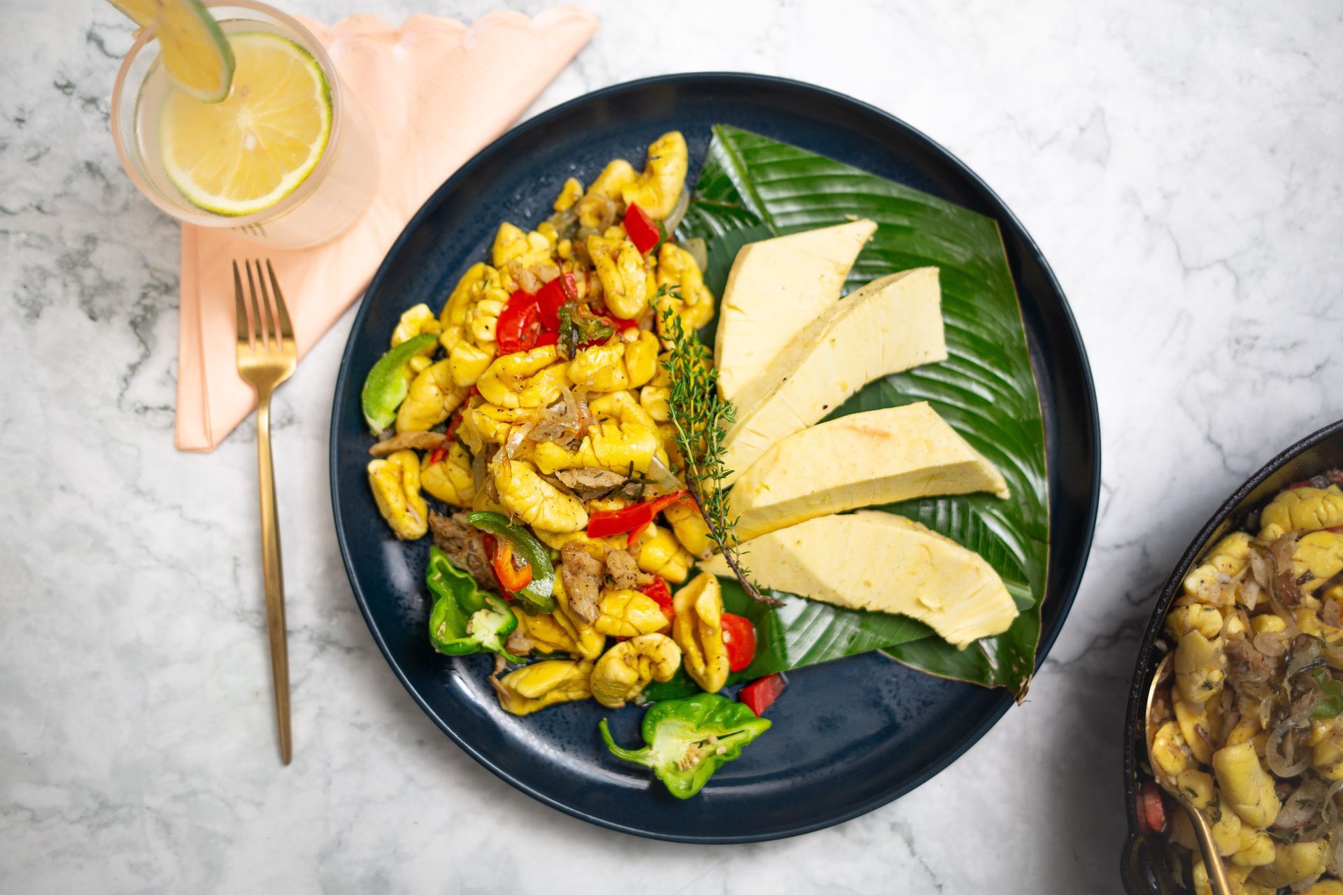 Gnocchi with vegetables and plantain on a blue plate with a drink and fork.
