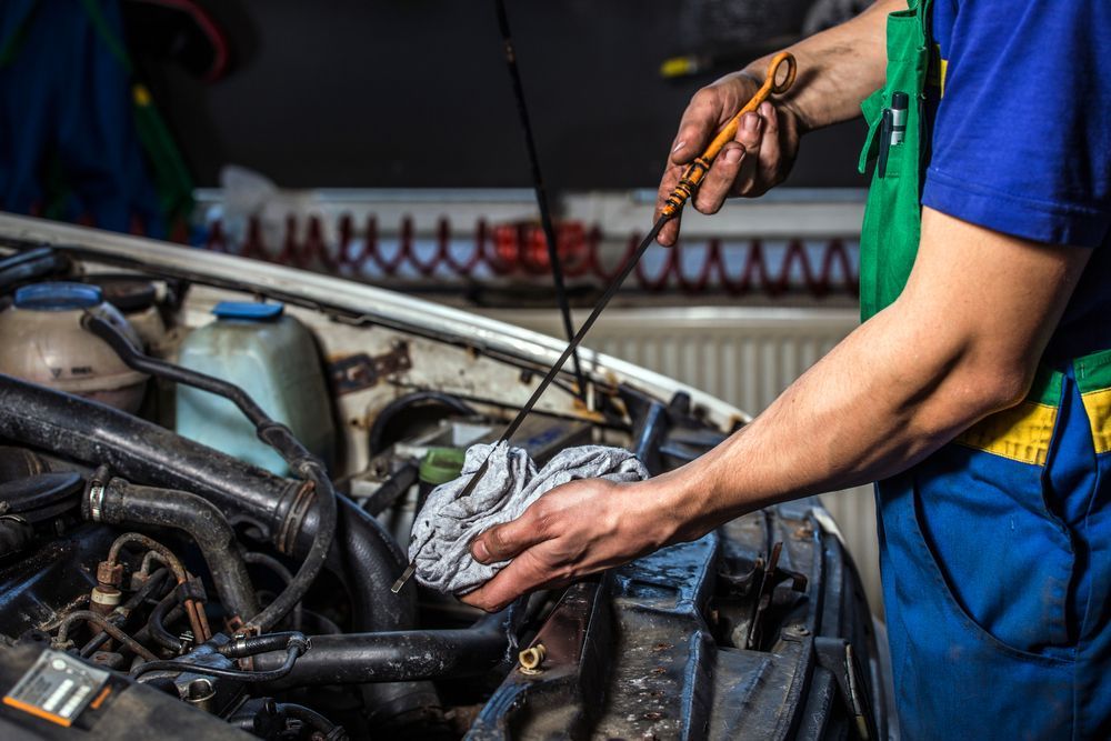 Mechanic Checking Oil Level in a Car Engine With Dipstick — EFI Evolutions Mechanical Repairs in Dubbo, NSW