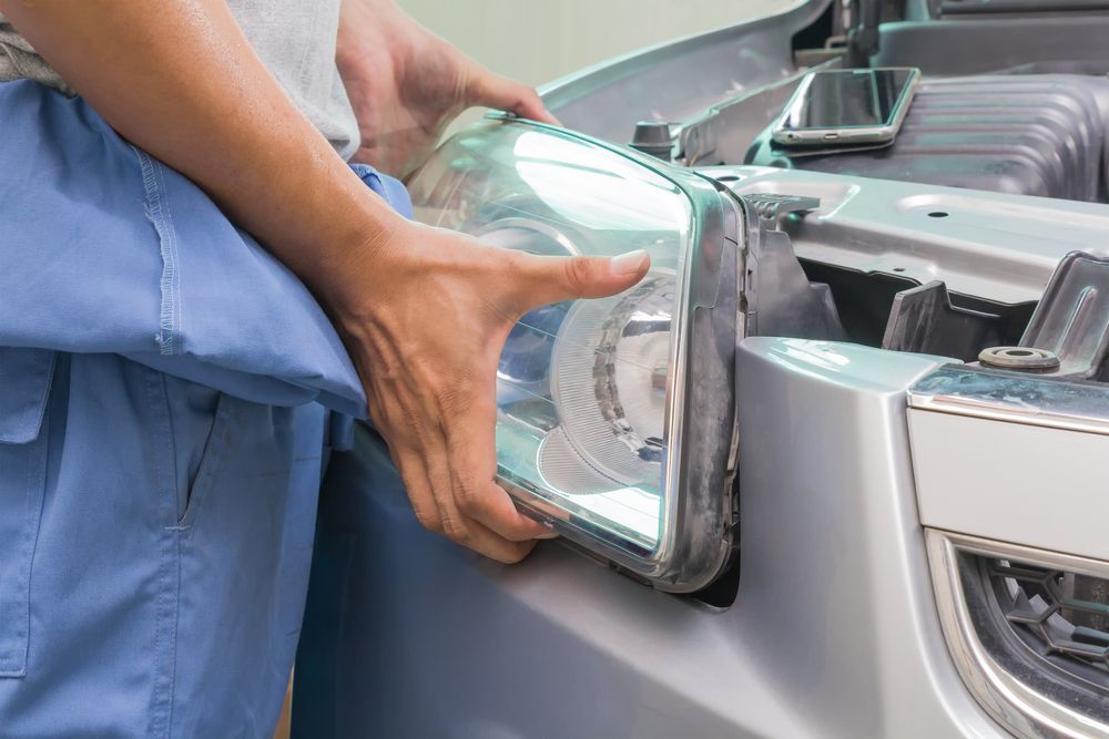 Person Removing a Car Headlight From a Silver Vehicle — EFI Evolutions Mechanical Repairs in Coffs Harbour, NSW