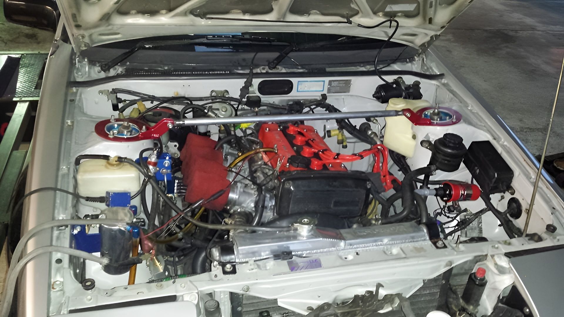 White Car Engine Bay With Red Strut Bar and Engine Components — EFI Evolutions Mechanical Repairs in Coffs Harbour, NSW