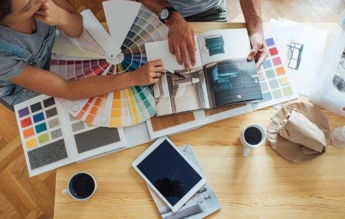 Handyman service consultation & free quote - Picture of a handyan and a clients looking at colour charts, fans and draw downs.