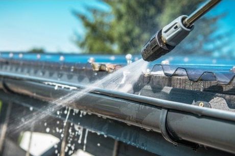Picture of a power washing want cleaning a gutter on a house.