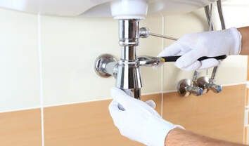 Handyman Richmond doing plumbing repair. The picture is of a sink pipe being tightened.