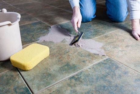 Tile Installation and repair - Handyman working to spread mortar to lay tiles on the floor using a grouting and tile tool.