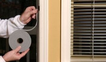 Picture of handyman weather stripping being installed on a door leaking air.