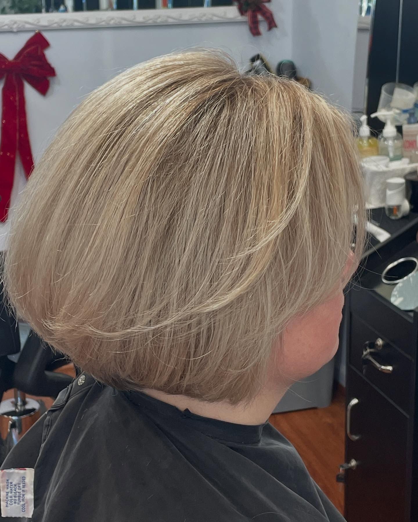 Woman with blonde bob haircut, profile view in a salon.