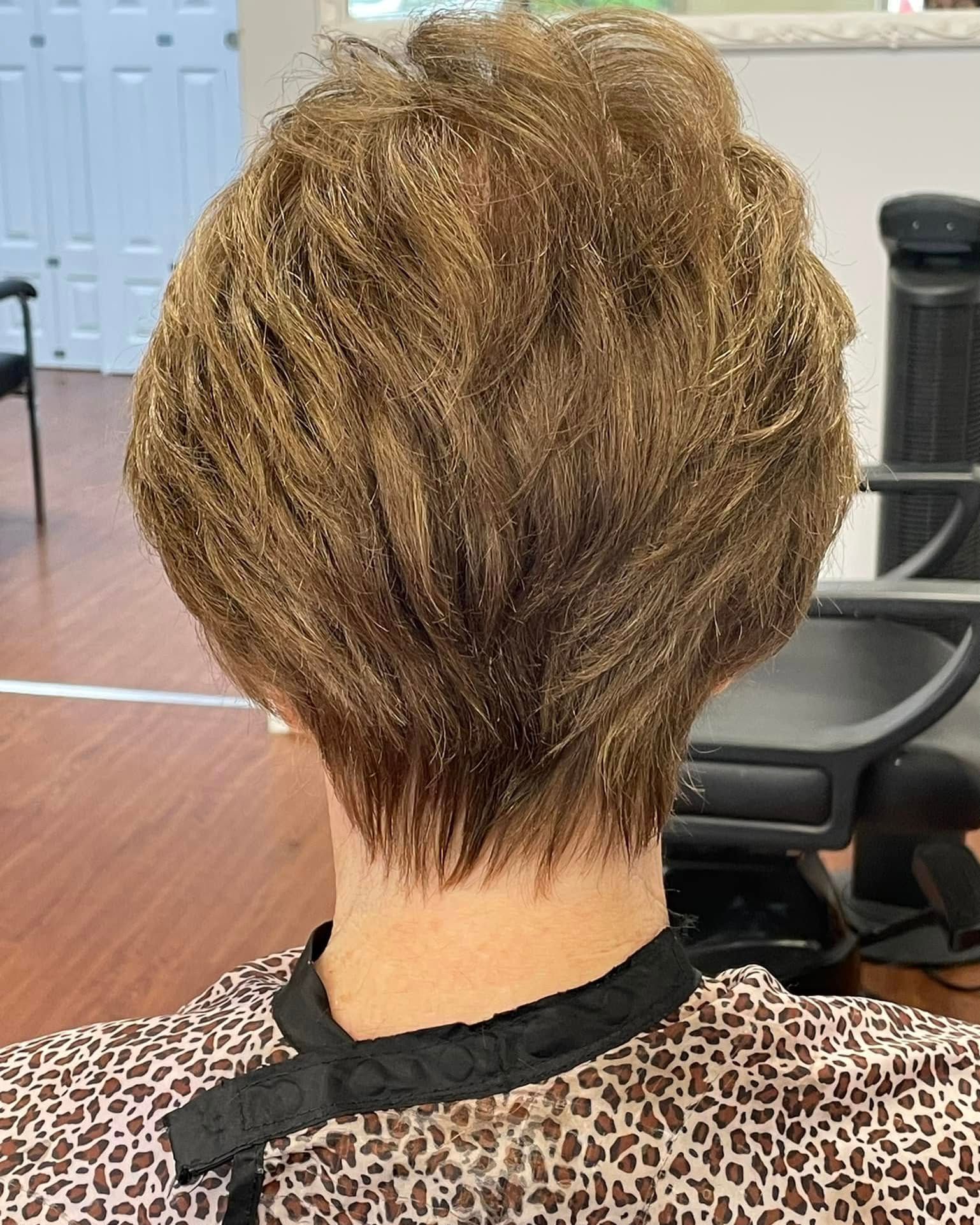 Back view of a woman with a short, layered, highlighted hairstyle and wearing a patterned cape.