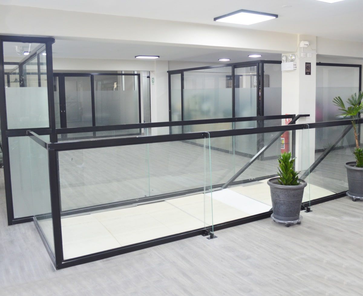 Interior de oficina moderno con barandillas de vidrio y metal negro y puertas de vidrio esmerilado.