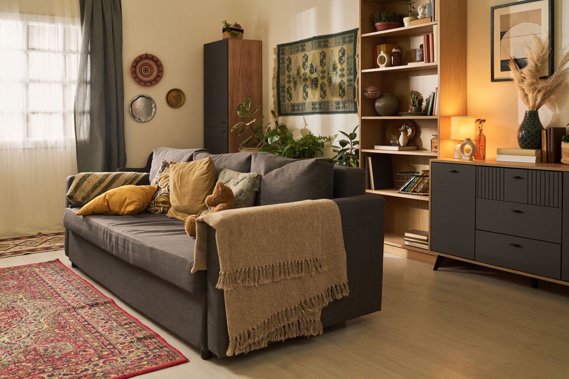 A cozy living room with an eclectic interior design style and layered drapes at the window 