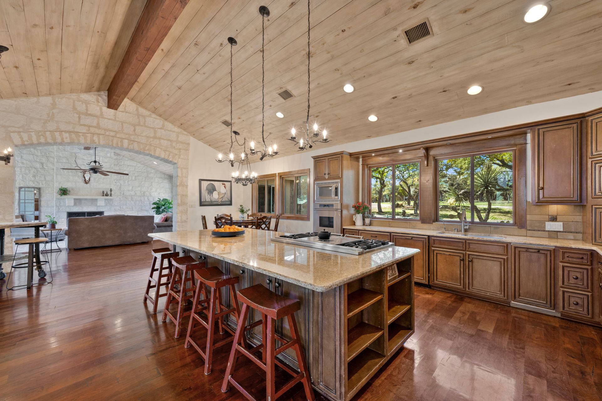 A farmhouse-inspired kitchen with a connecting living room and large windows in need of covering 