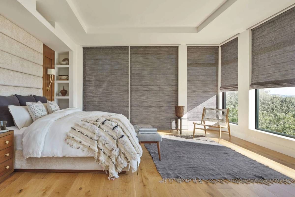 Alustra® Woven Textures® Roman Shades in various degrees of openness on windows in a stylish bedroom