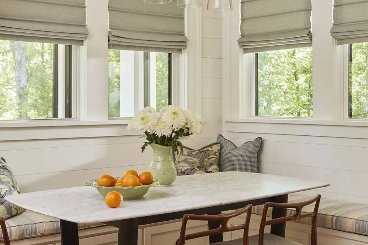 Carole™ Fabrics Roman Shades on several windows in a breakfast nook of a home