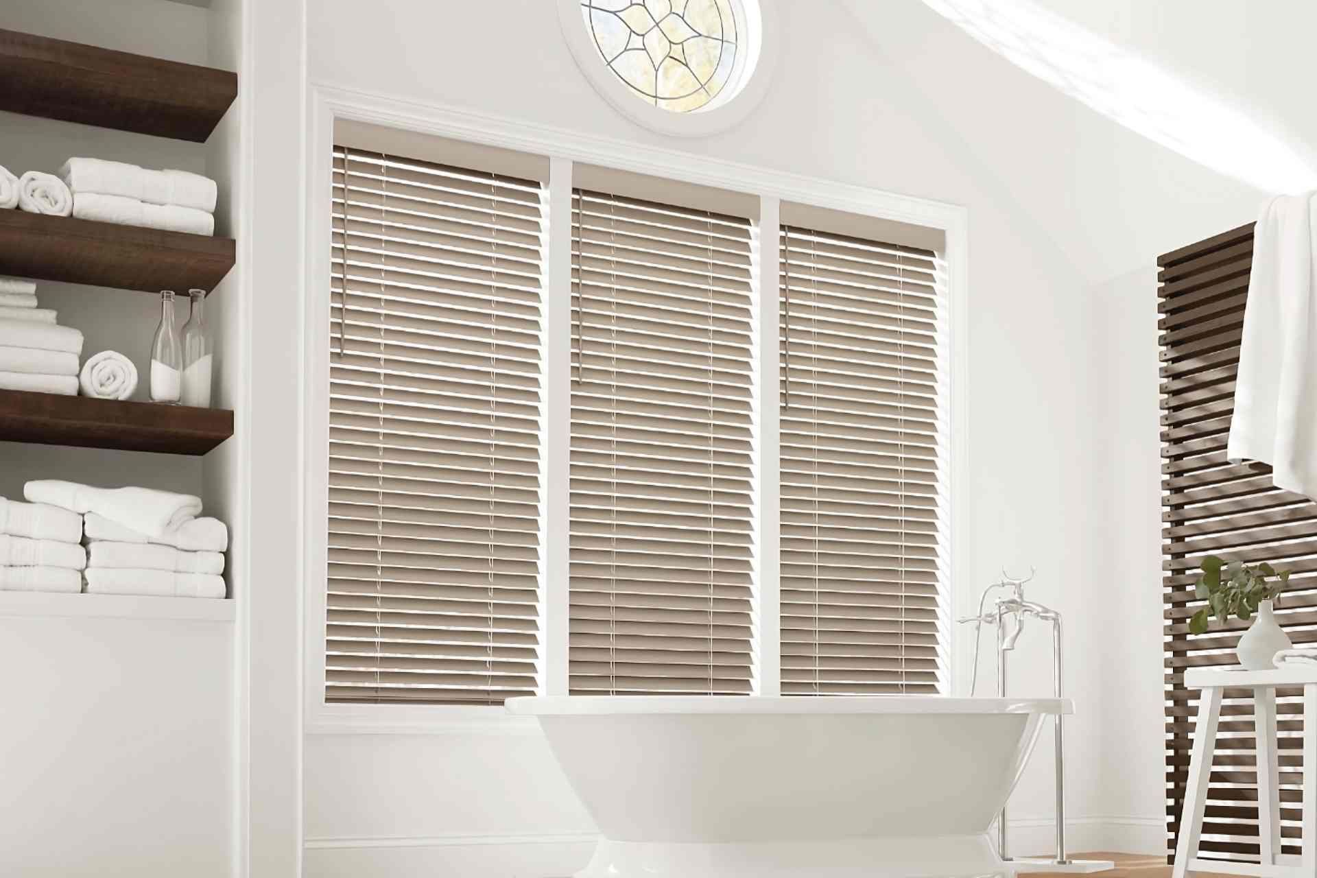 Hunter Douglas EverWood® Faux Wood Blinds on tall windows in a bathroom with a free-standing tub at Curtain Concepts near Huntington, WV