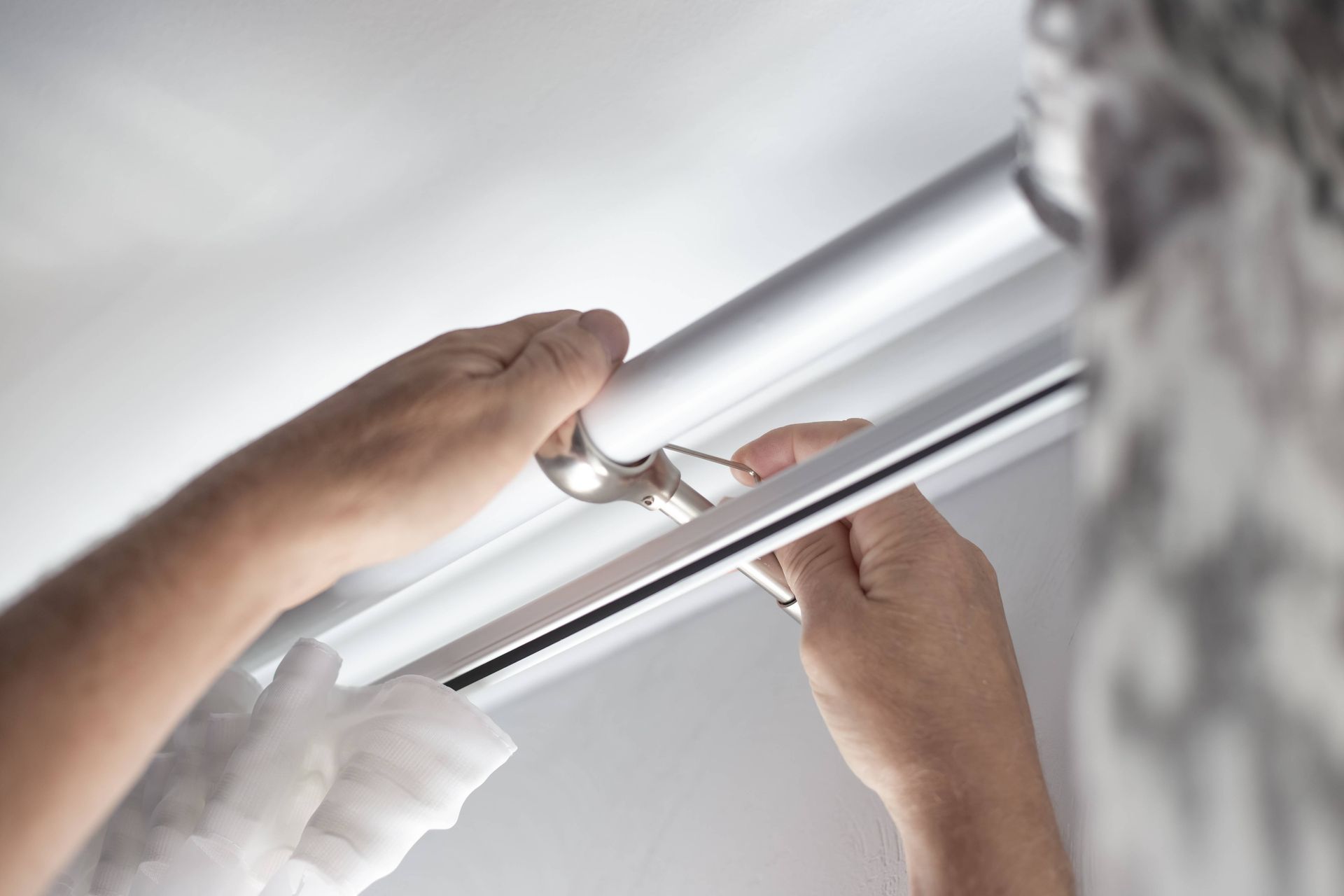 Drapery professional installing a curtain rod to a homeowner's wall to hang their soft window treatm