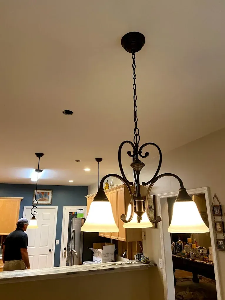Dining room with hanging chandelier lights and open kitchen in the background