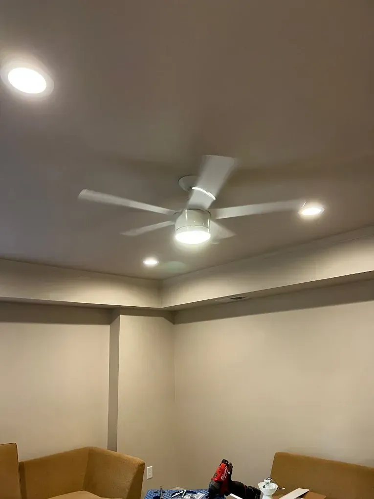Living room with beige walls, tan couches, recessed lights, and a ceiling fan.