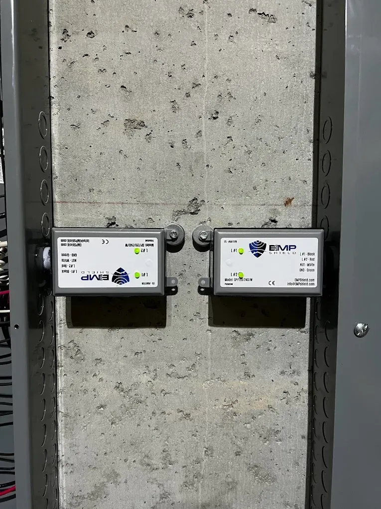 Two small white utility boxes mounted on a concrete wall in a server room or industrial setting