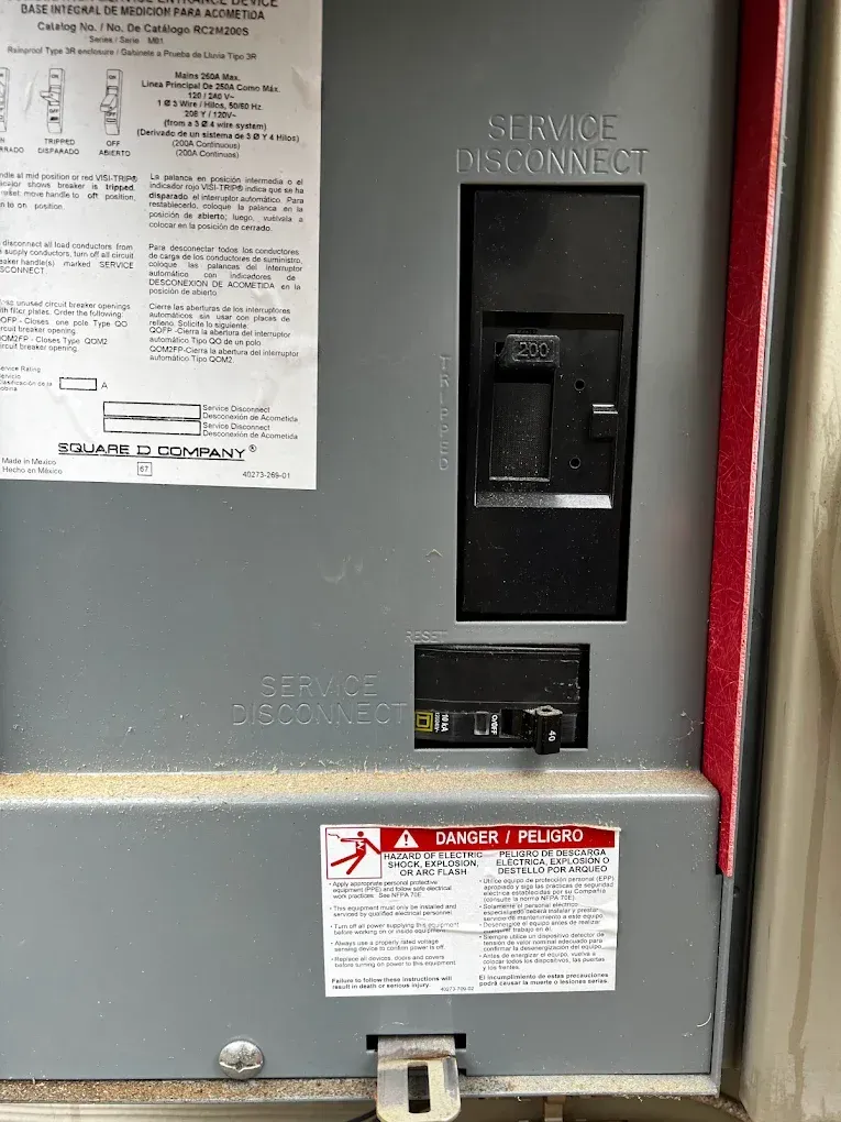 Gray electrical panel with breaker switches, warning labels, and a red trim edge