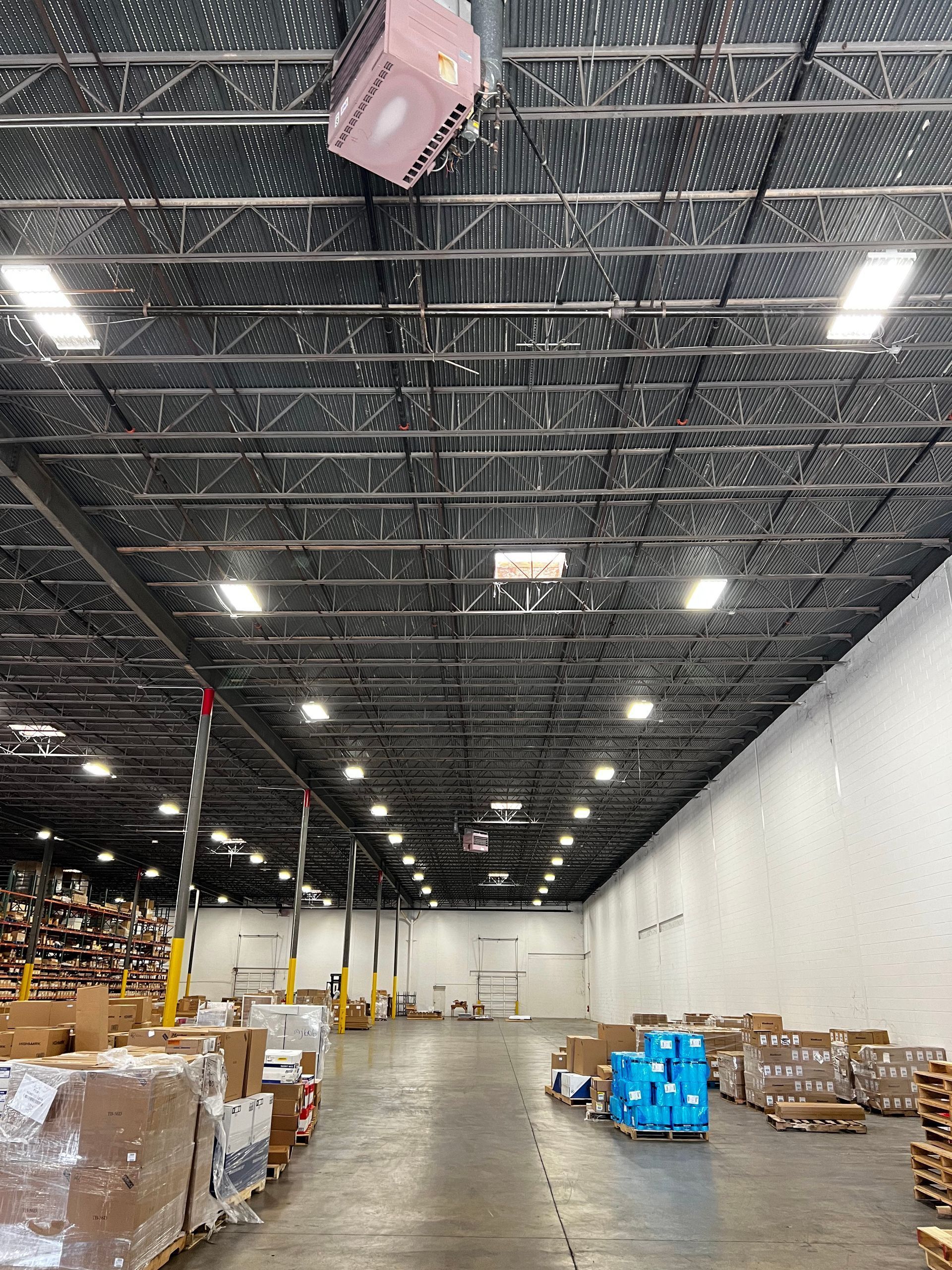 Large warehouse interior with stacked pallets and boxes under bright ceiling lights