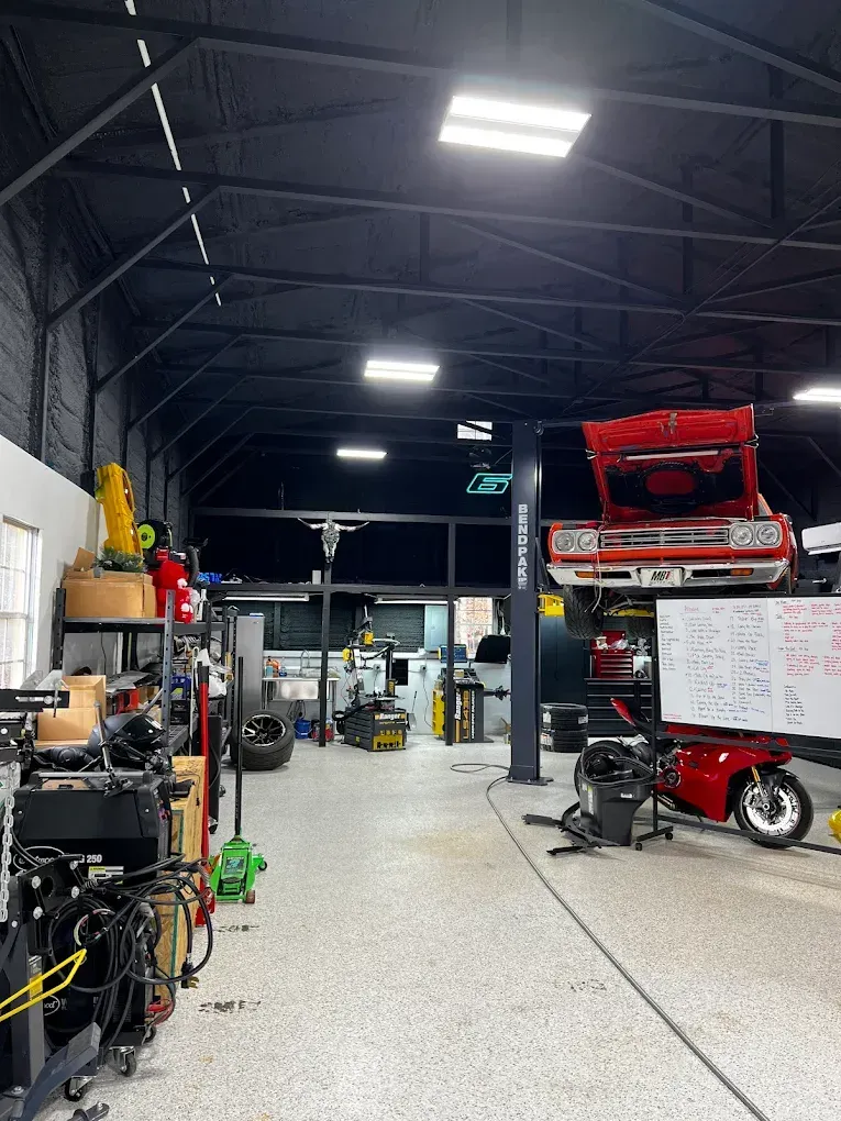Auto shop interior with raised red truck and tools along the walls