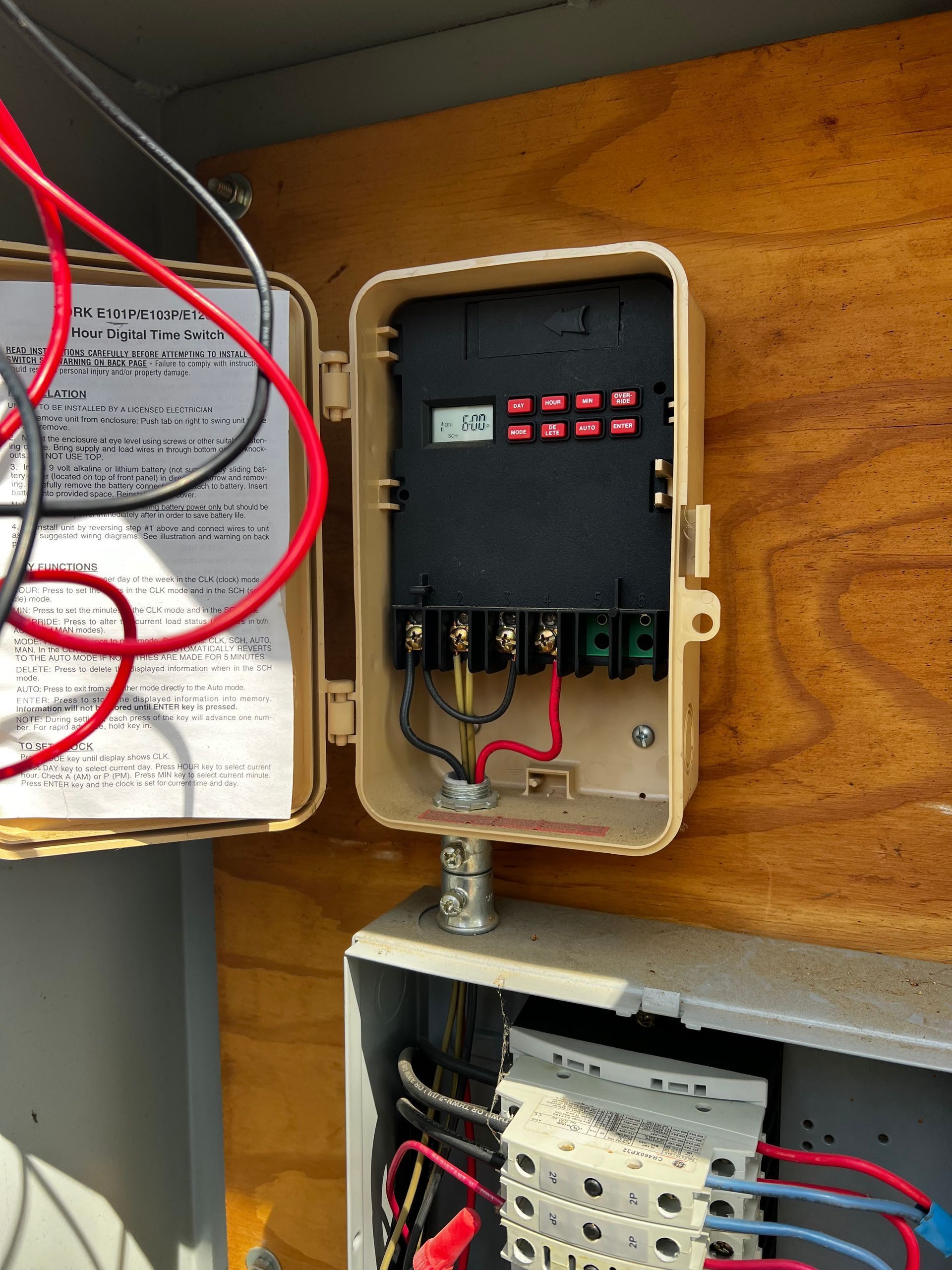Open electrical control boxes with wiring and labeled components mounted on a wall.
