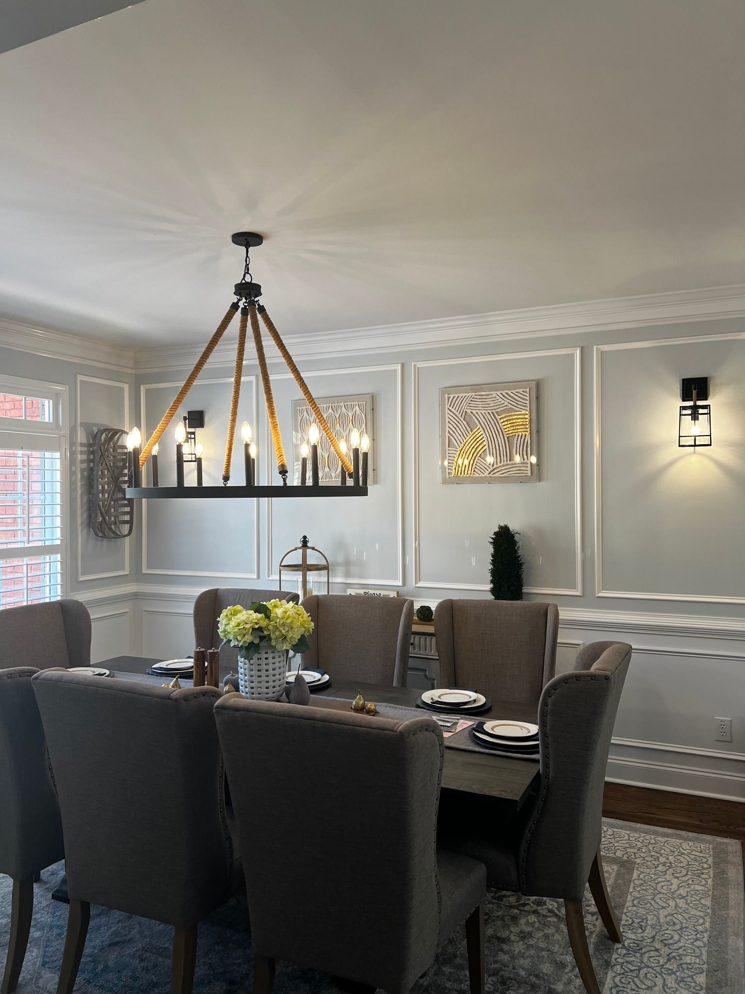 Elegant dining room with gray chairs, chandelier, and framed wall art in soft neutral tones