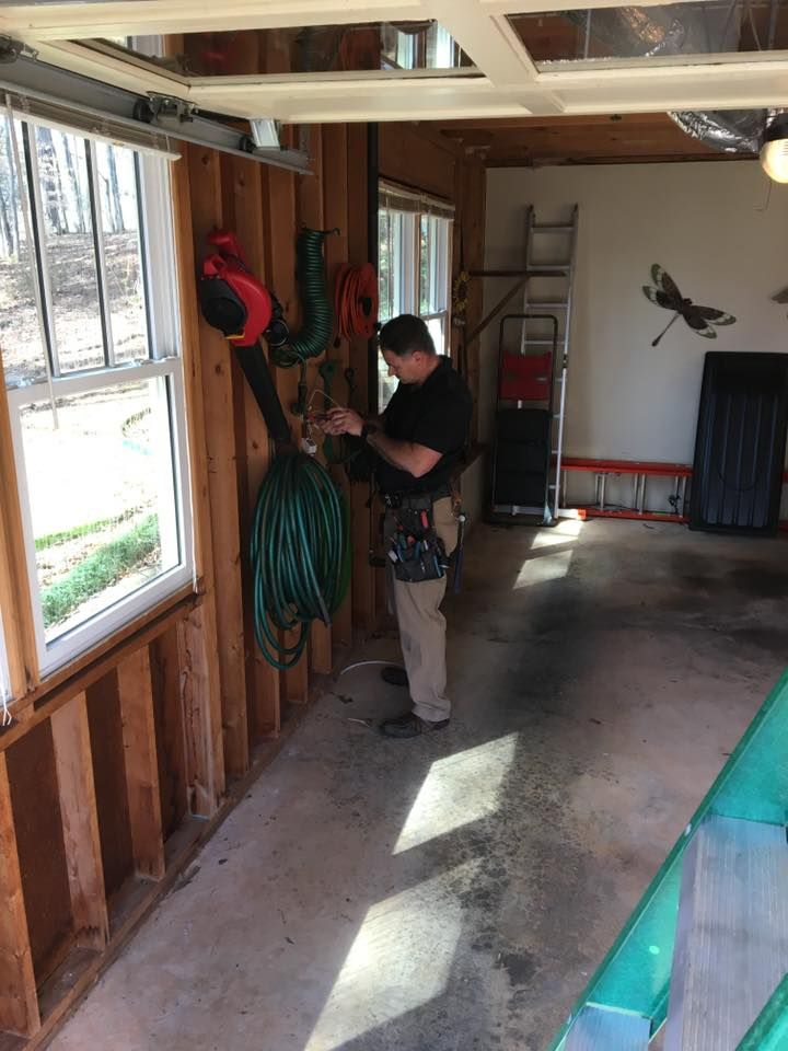 Person hanging decorations in a garage with exposed studs and a window on the left.