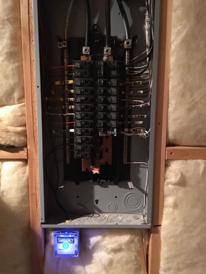 Open electrical breaker panel with wiring and a glowing digital meter at the bottom