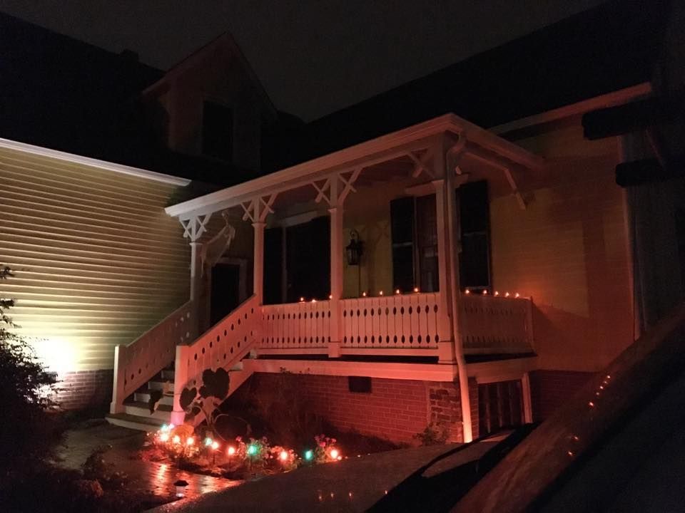 Porch of a house decorated with orange Halloween lights at night