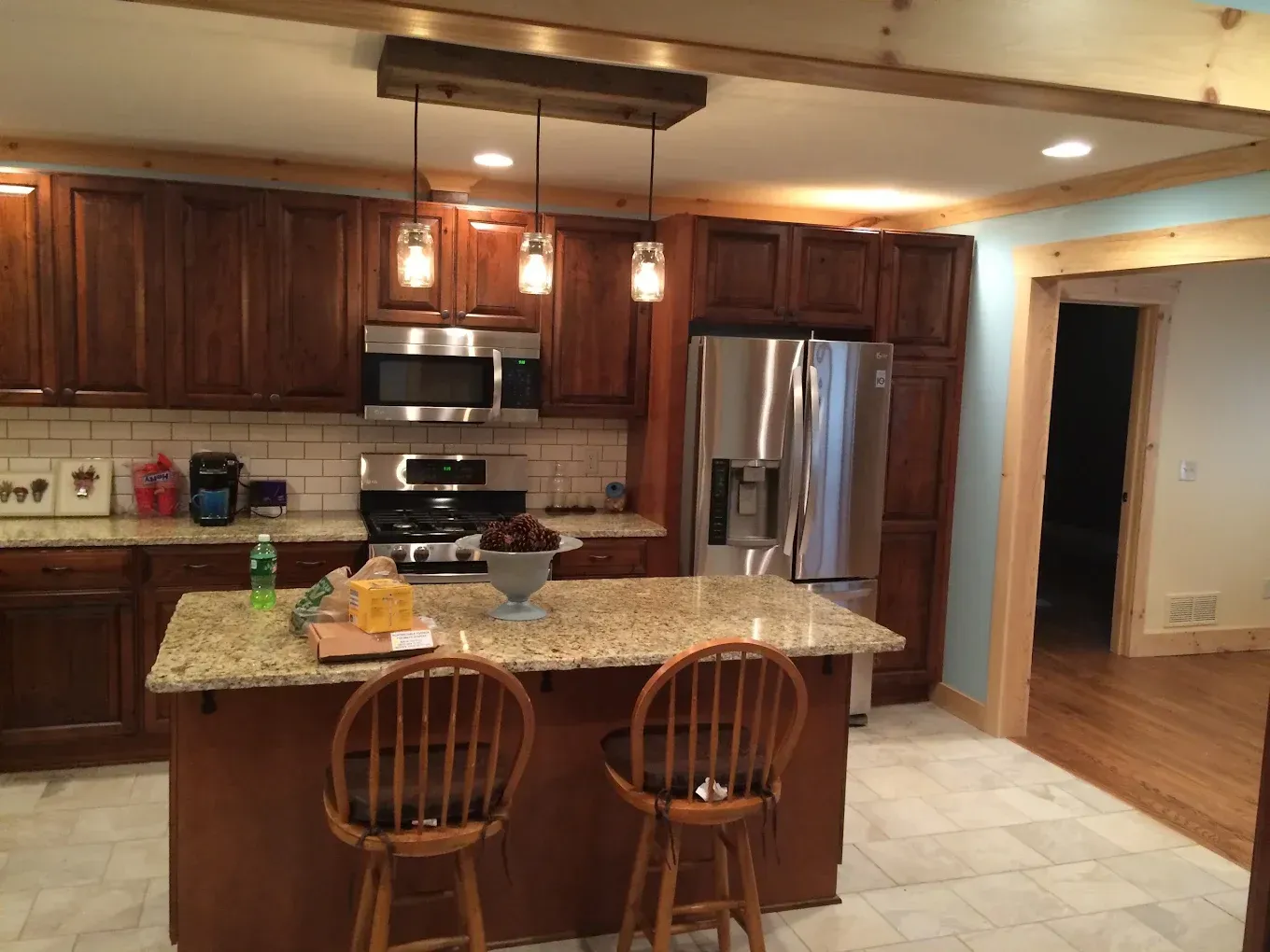 Modern kitchen with granite island, wooden cabinets, stainless steel appliances, and two bar stools