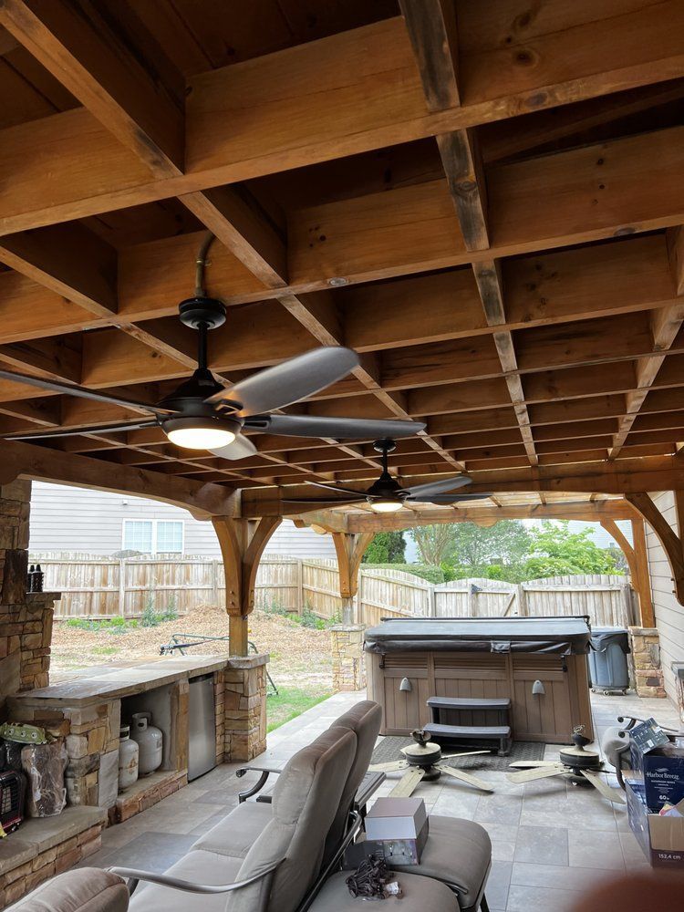 Covered backyard patio with wood ceiling, ceiling fans, outdoor kitchen, seating, and hot tub