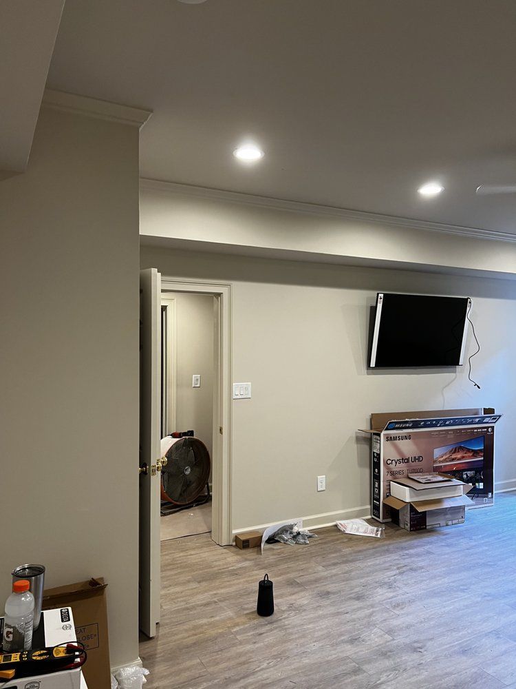 Empty living room with wall-mounted TV, recessed lights, and a doorway to a hall.