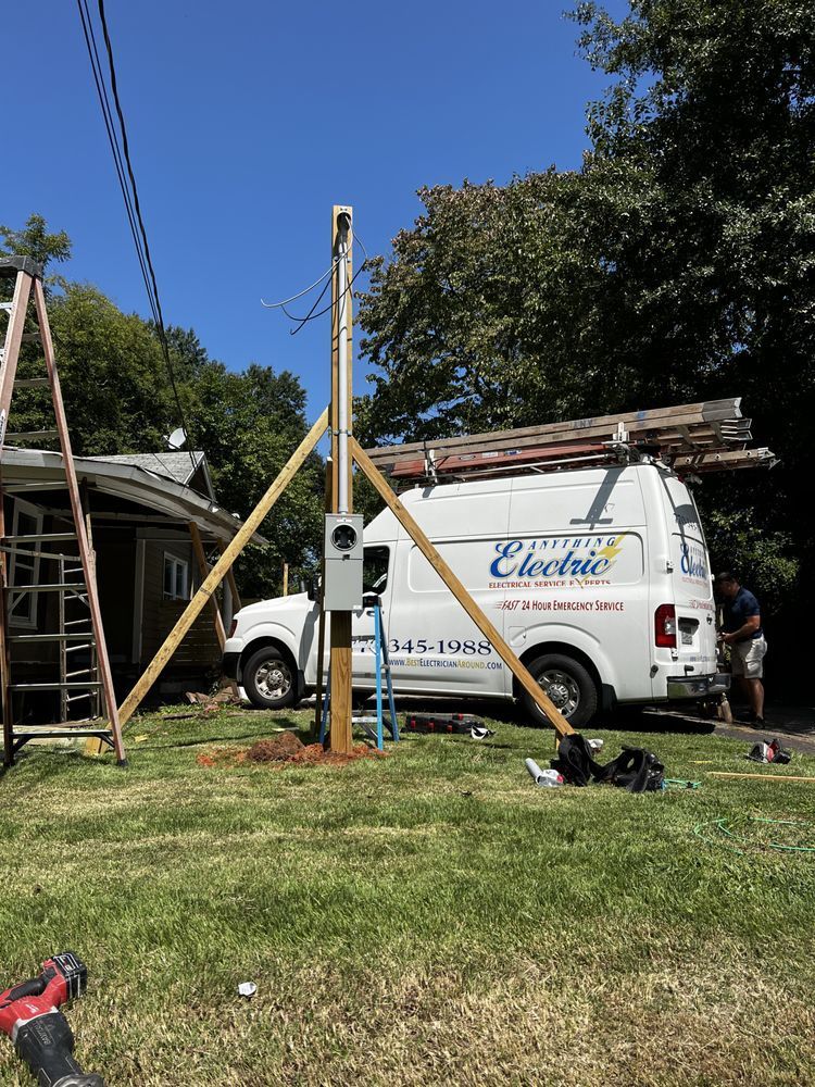White utility van in a yard with ladders and poles, under construction work in bright daylight