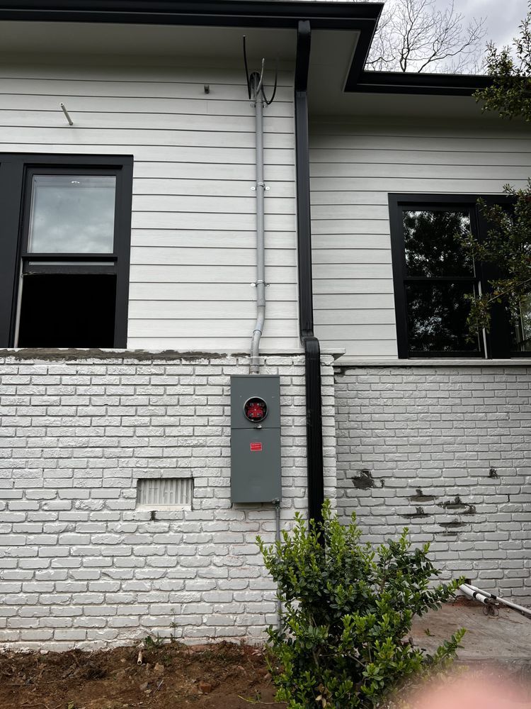 Gray utility meter box on a white brick house exterior beneath two windows.