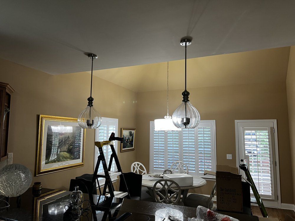Dining room with large windows, glass table, hanging lights, and exercise equipment by the walls.