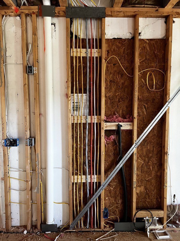 Exposed wall framing with electrical wiring, insulation, and a diagonal metal support beam in a renovation area