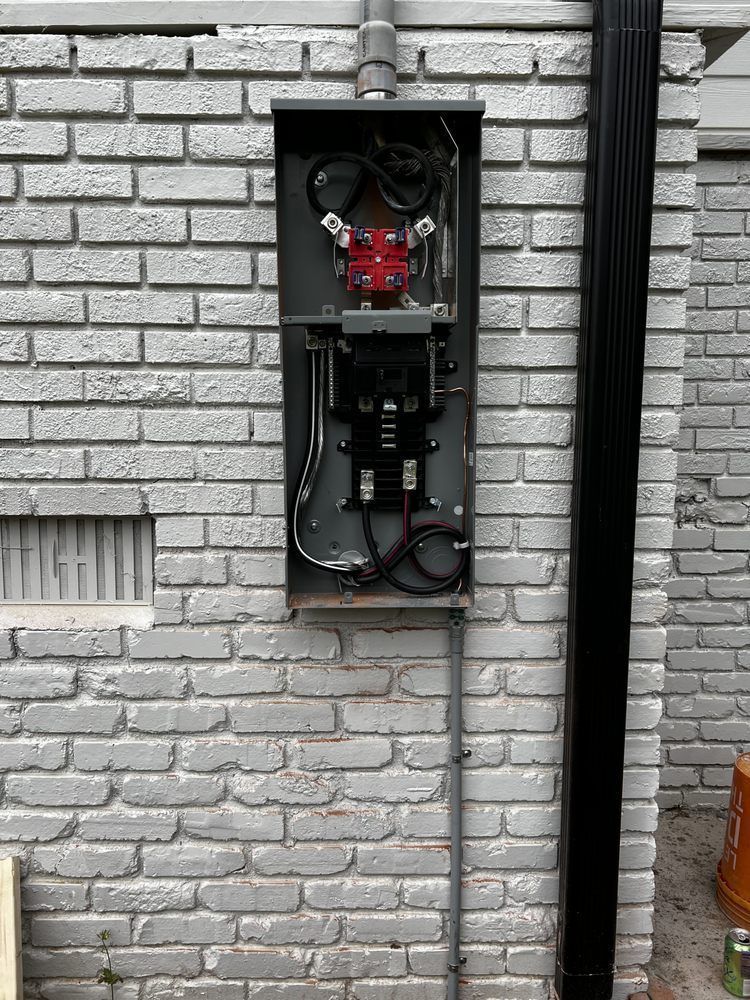 Open utility box on a brick wall with exposed wires and electrical components