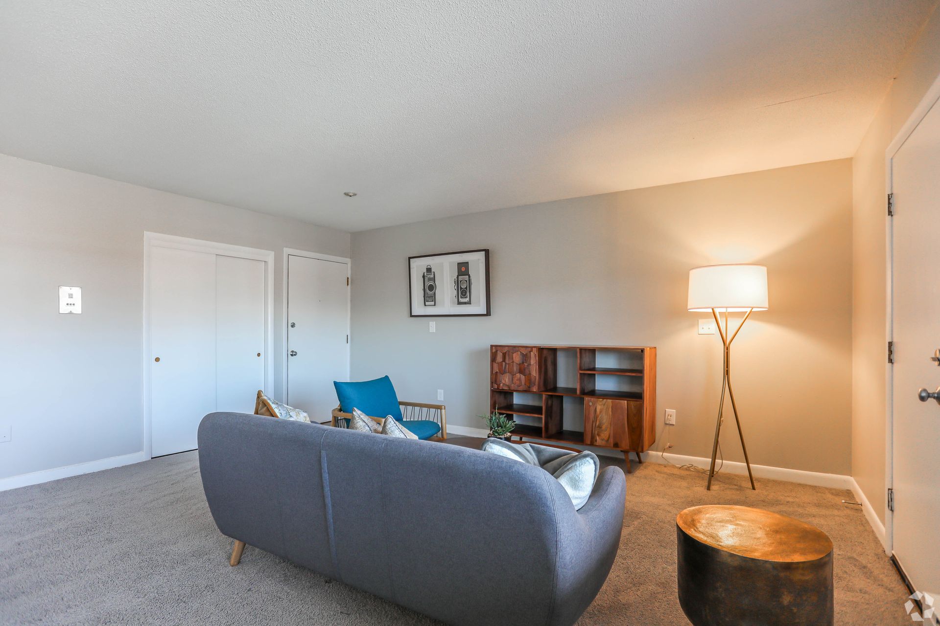 Living room with gray couch, wooden cabinet, floor lamp, and white doors.