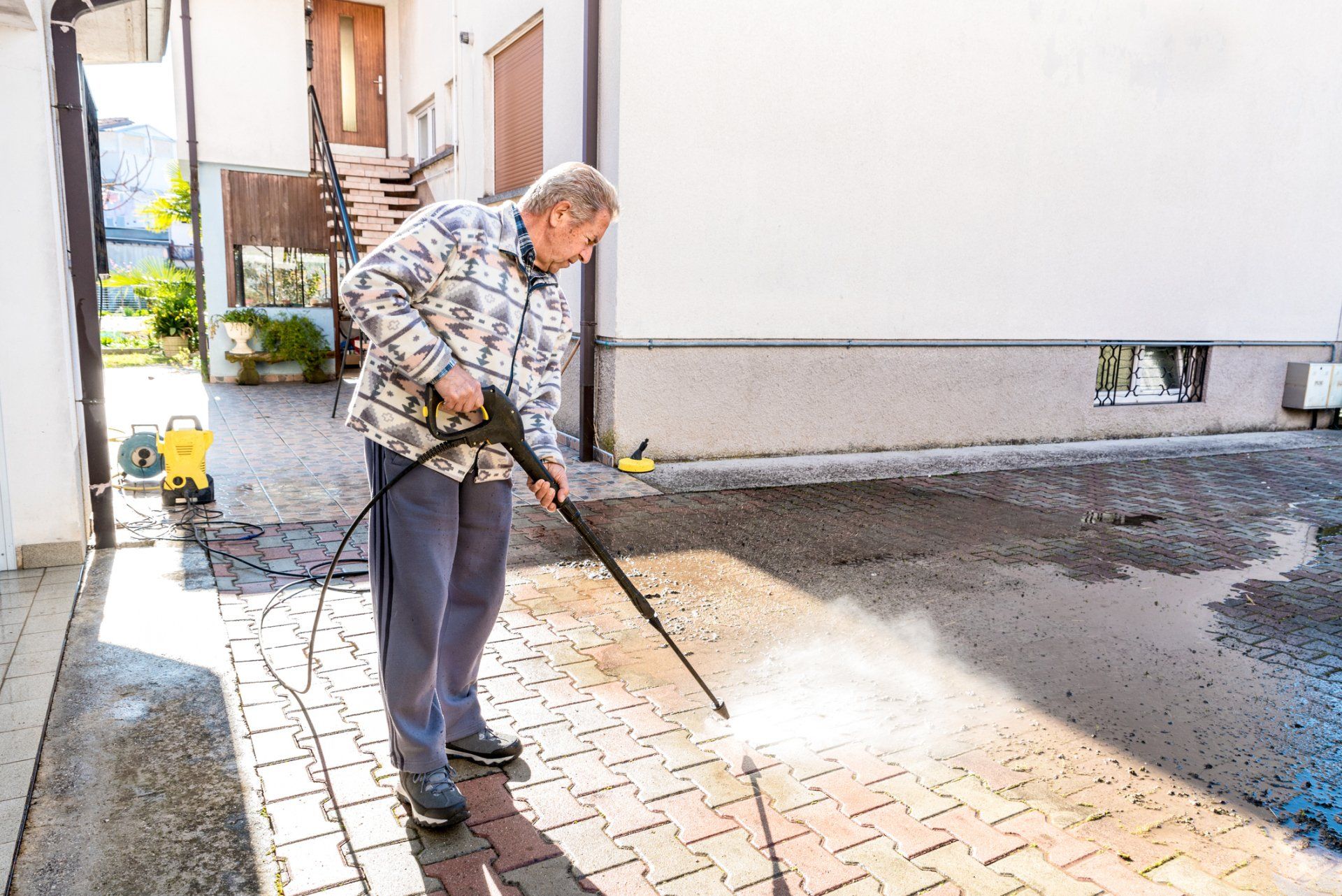 Senior Man Cleaning the Back Yard with High-Pressure Washer — Garfield, GA — Southeast Soft Wash Solutions Senior Man Cleaning the Back Yard with High-Pressure Washer — Garfield, GA — Southeast Soft Wash Solutions