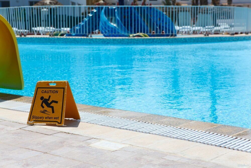 A Caution Sign is Sitting Next to a Swimming Pool — Affinity Swim in Norman Gardens, NSW