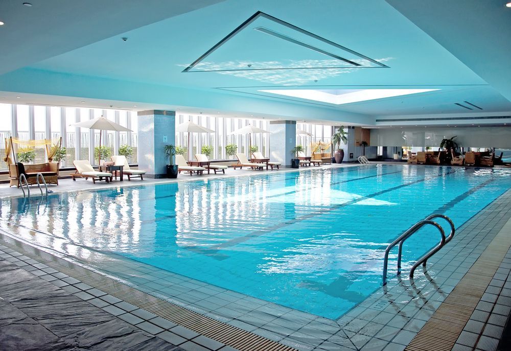 A large indoor swimming pool with chairs and umbrellas around it — Affinity Swim in Norman Gardens, NSW