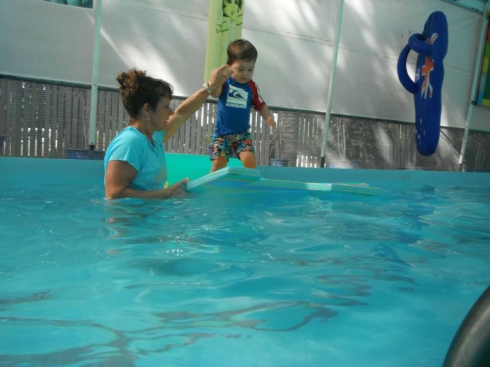 A Woman is Helping a Young Boy Jump Into a Swimming Pool — Affinity Swim in Norman Gardens, NSW