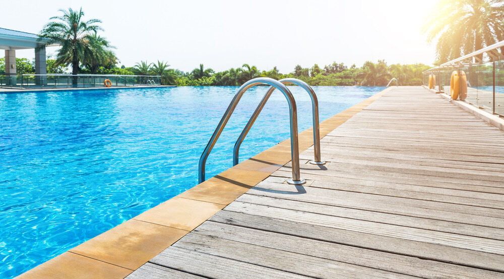 A Swimming Pool With a Wooden Deck and Stairs Leading to It — Affinity Swim in Norman Gardens, NSW