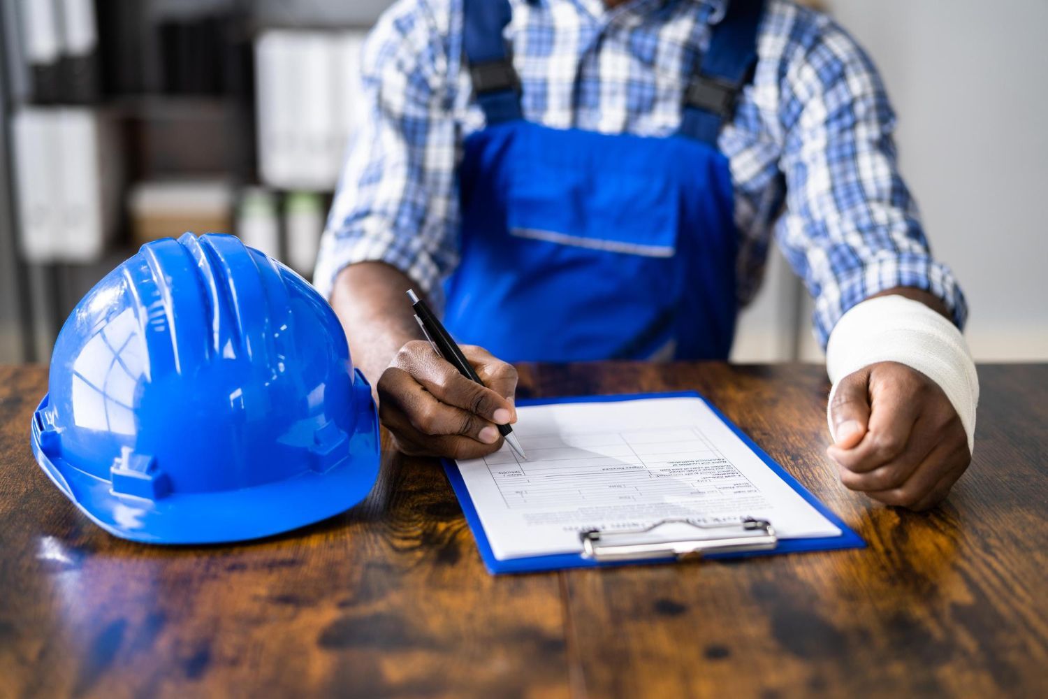 Construction worker reviewing plans at a desk with a blue hard hat beside them