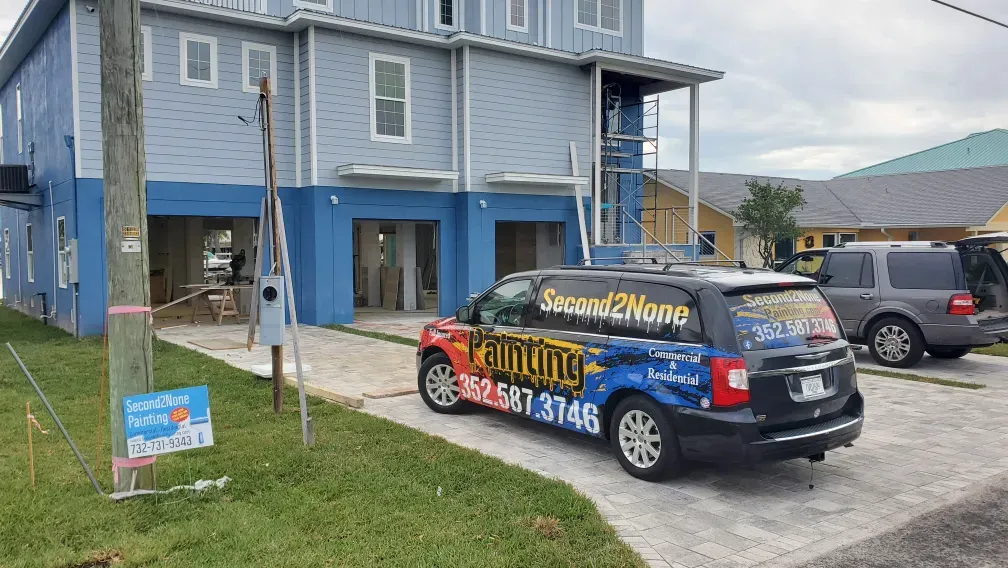 A blue two-story house with a van that says