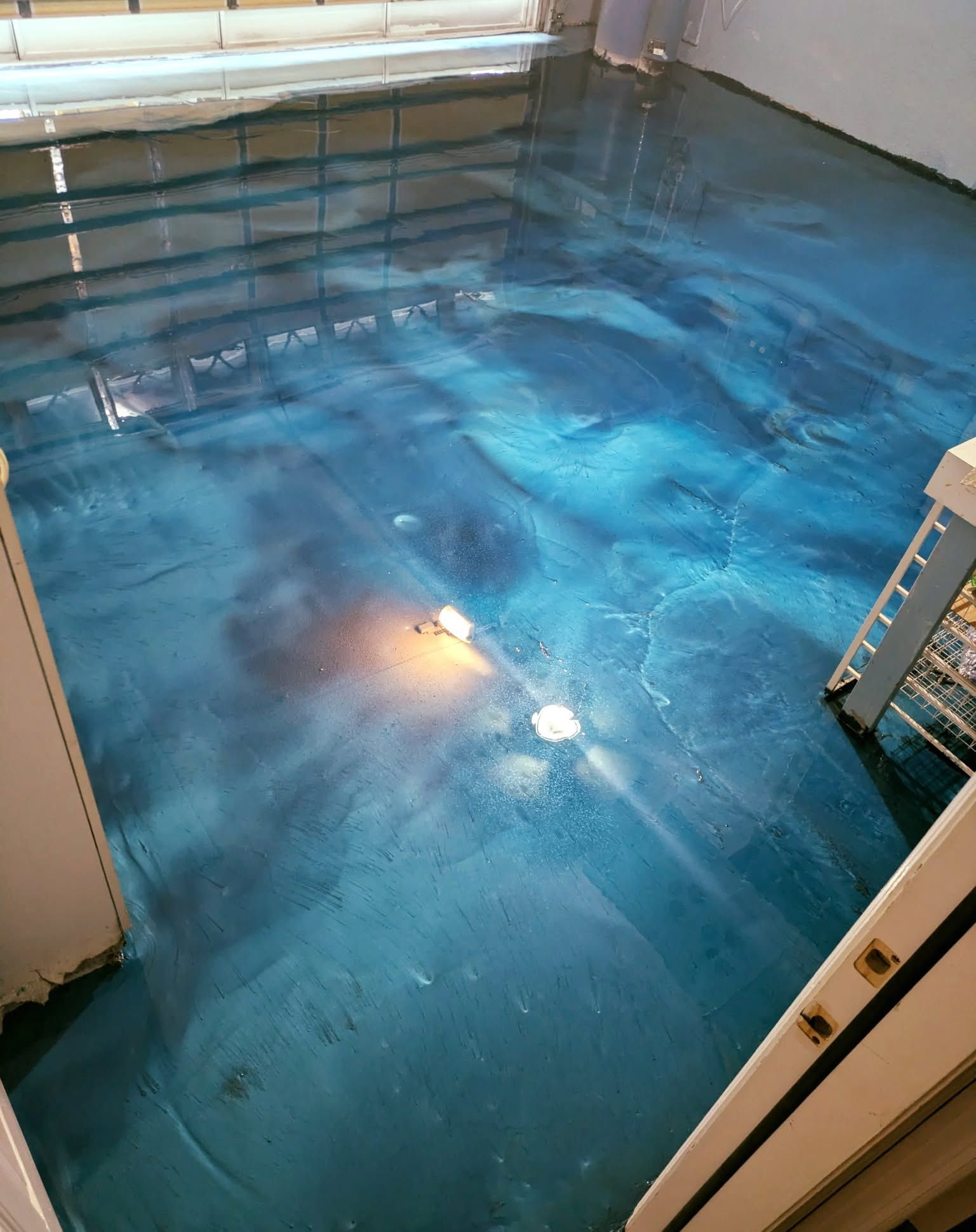 Blue epoxy floor with swirling patterns, reflecting light in a room.