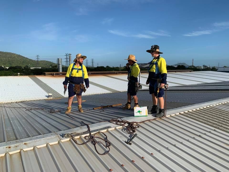 Three Men Are Standing on Top of a Metal Roof — Northern Plumbing In Mount Louisa, QLD