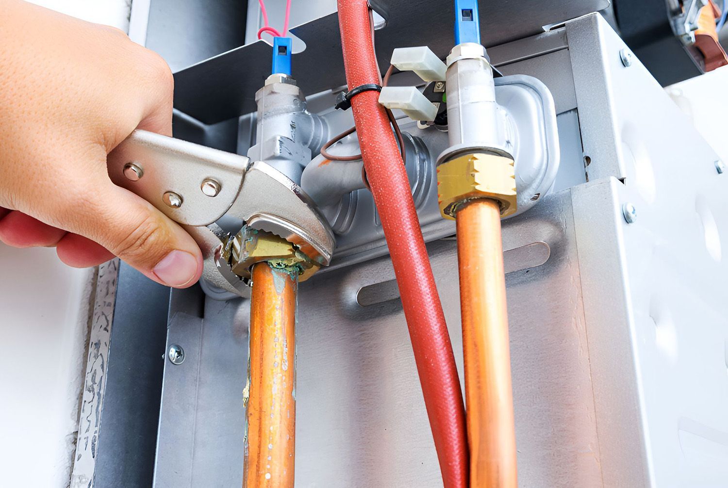 Hand Using A Wrench To Tighten A Brass Fitting On Copper Pipes