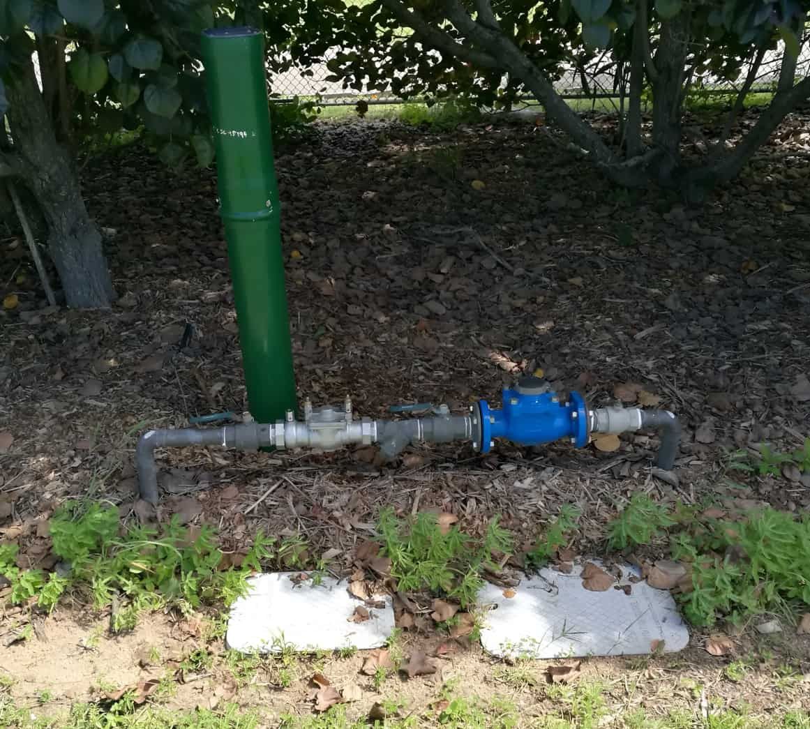 A Blue Water Meter is Attached to a Green Pipe — Northern Plumbing In Mount Louisa, QLD